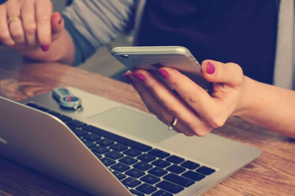 パソコンの前でスマホを操作する女性