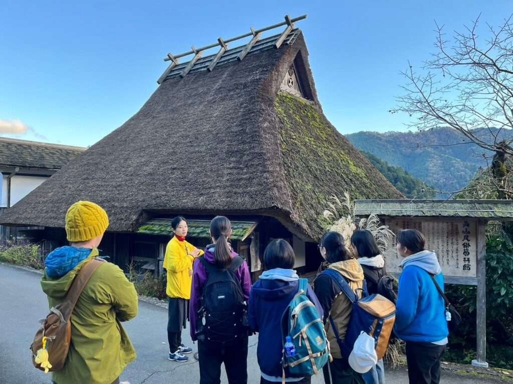 美山DMO事務局長の高御堂和華さんがかやぶきの里を案内している様子